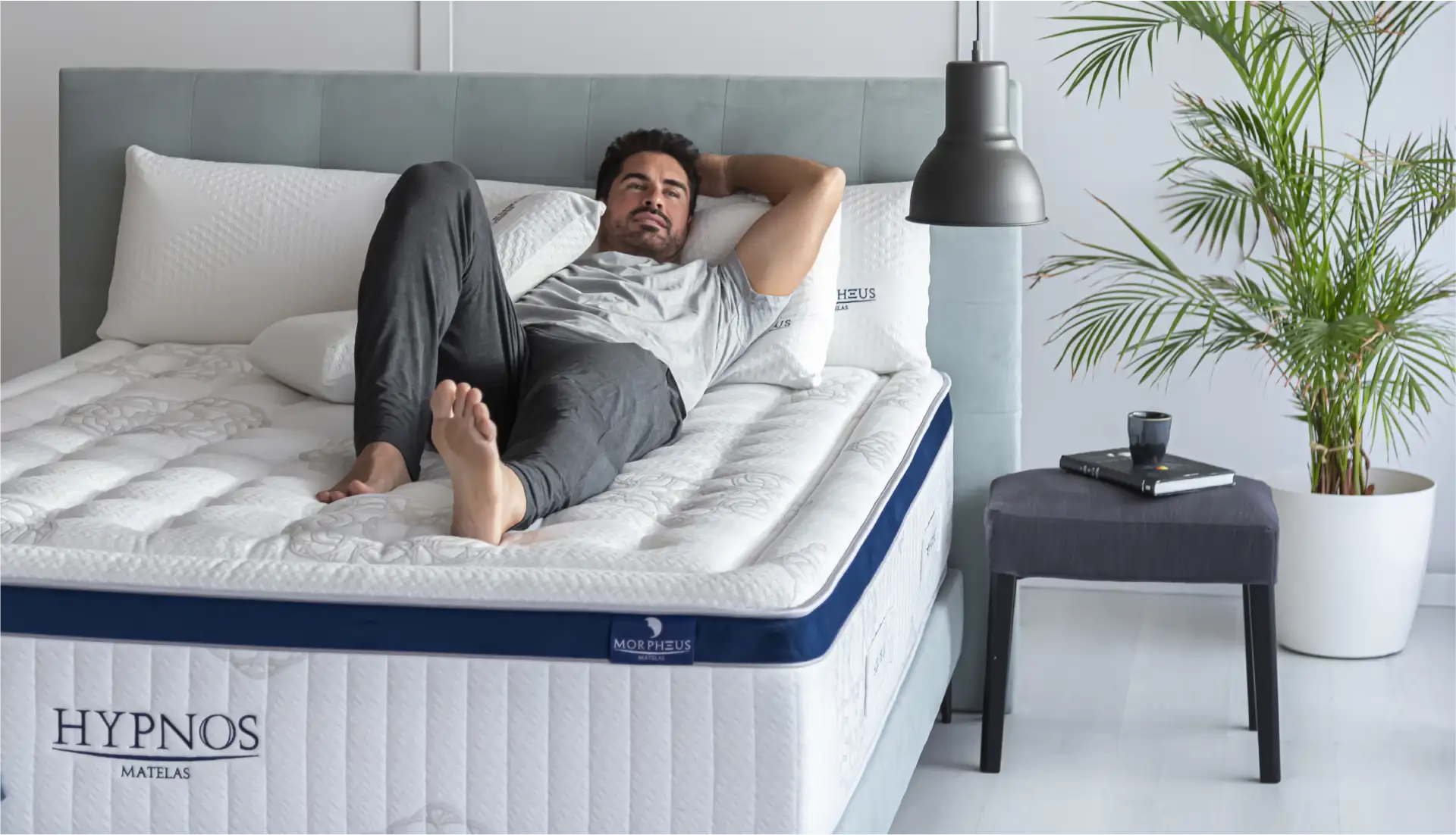 Homme seul allongé dans son matelas Hypnos avec ses oreillers confort Morpheus