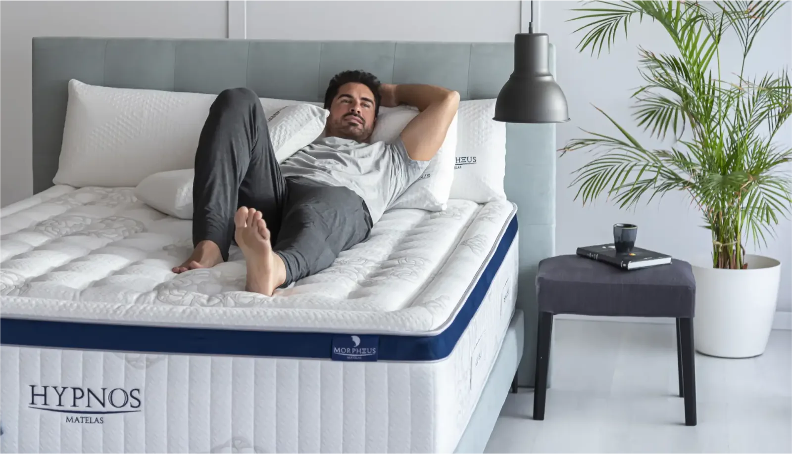 Homme seul allongé dans son matelas Hypnos avec ses oreillers confort Morpheus