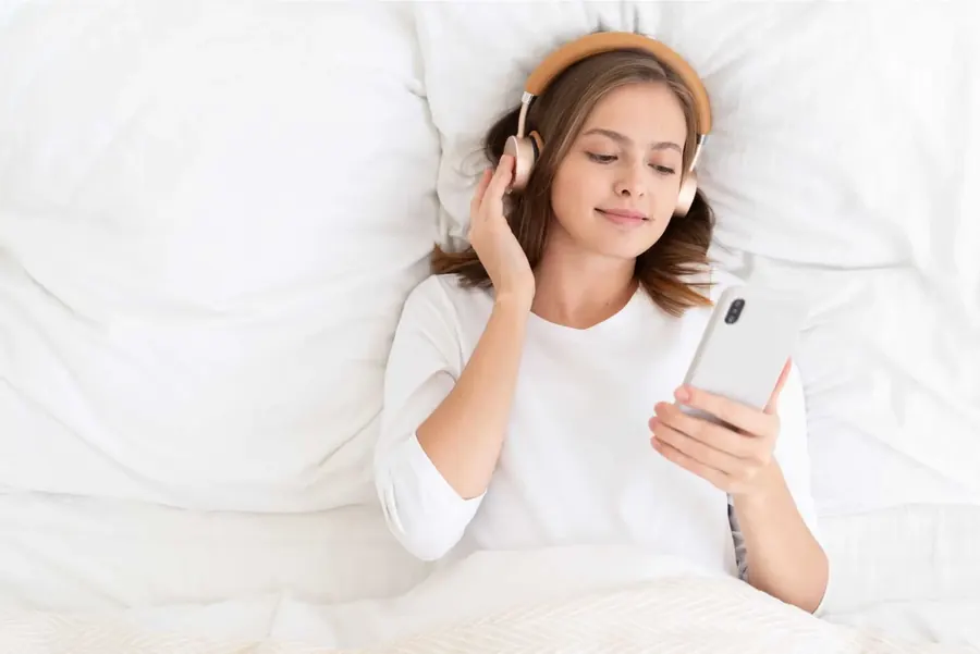 Femme écoutant de la musique dans son lit