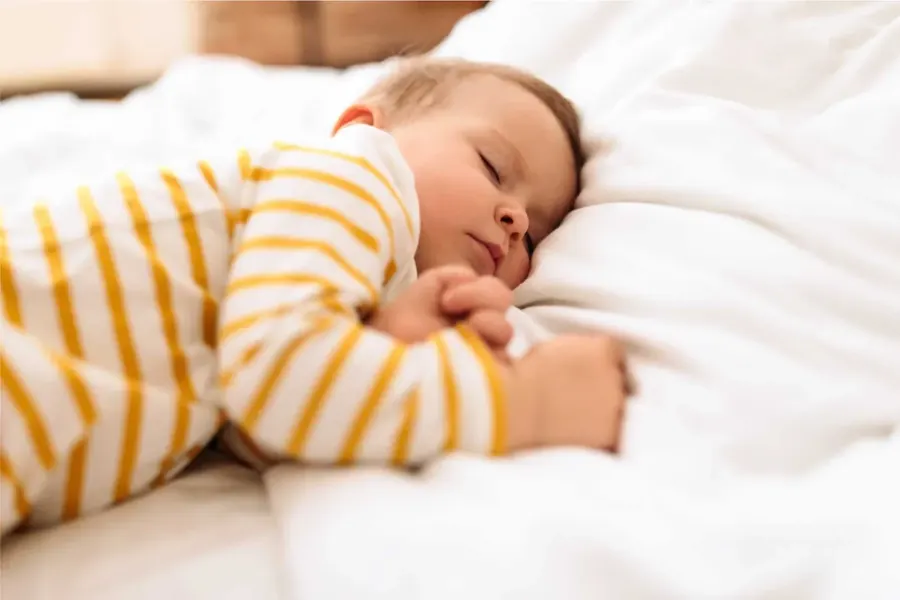 Bébé endormi dans un lit blanc