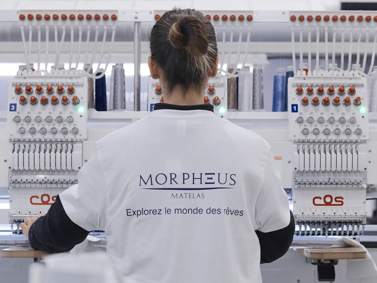 Opératrice en t-shirt Morpheus devant les machines à broder de l’usine Morpheus de Yecla, en Espagne